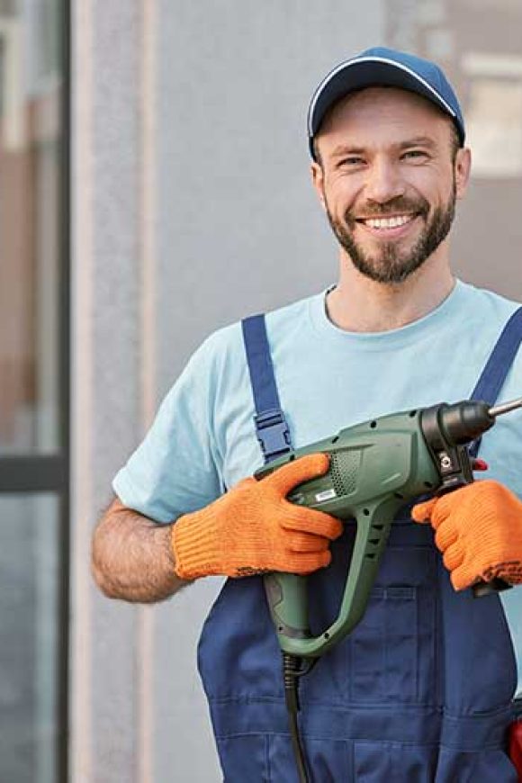 cheerful-male-worker-holding-electric-drill-machin-2022-09-22-18-48-55-utc